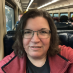 Elise MacDonald, a white woman with glasses on board a commuter train
