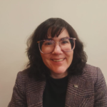 Margot Nikitas, a light-skinned woman with glasses and a tweed suit